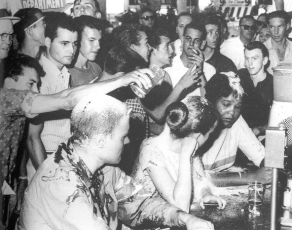 Protesters at a lunch counter sit-in at Woolworths in Little Rock, Arkansas, 1963, under assault from a white mob. The protesters were beaten, kicked, and burned with cigarettes. The assault lasted three hours, while police stood by.
